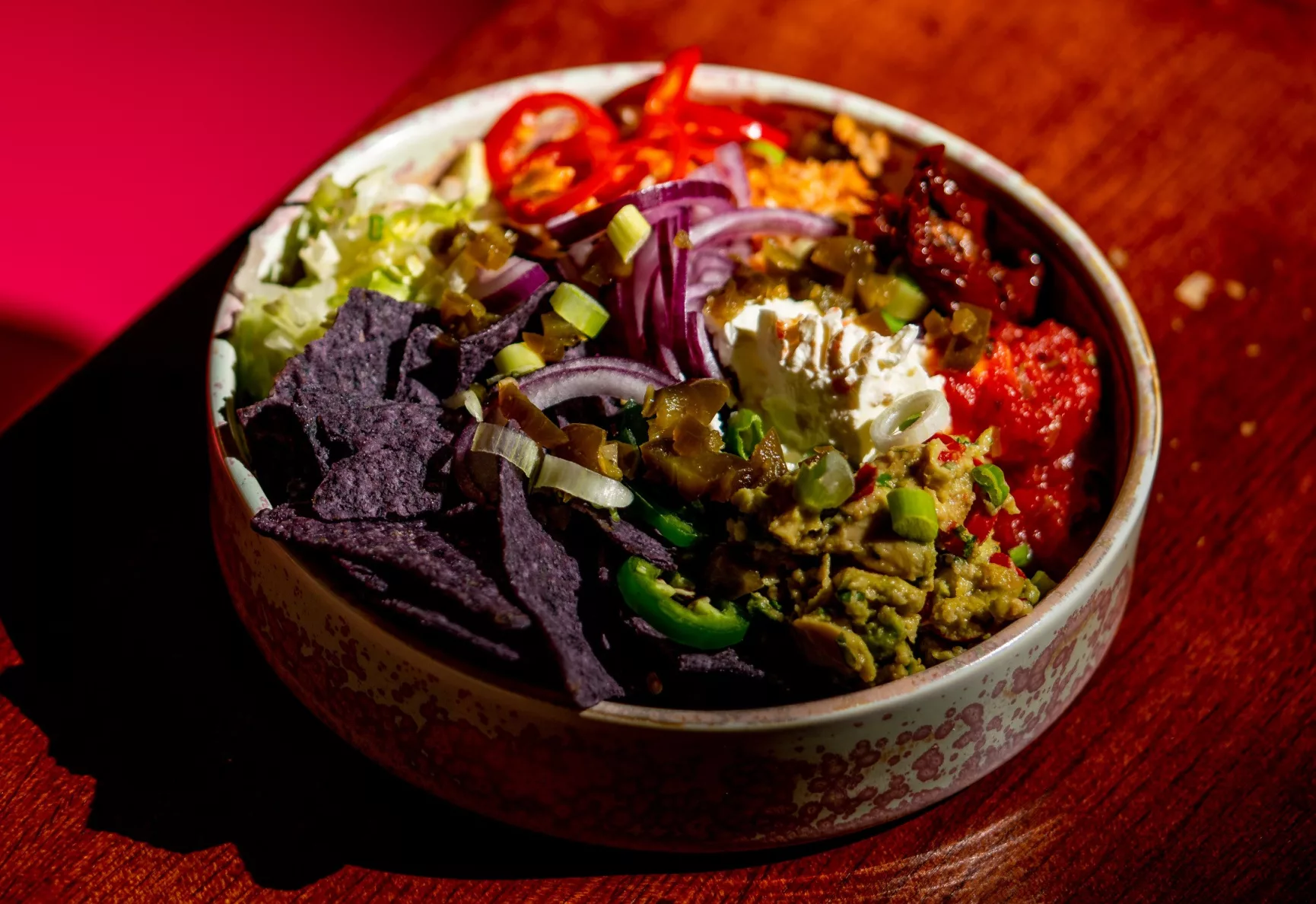 A vibrant nacho bowl with purple tortilla chips and loads of gorgeous sides