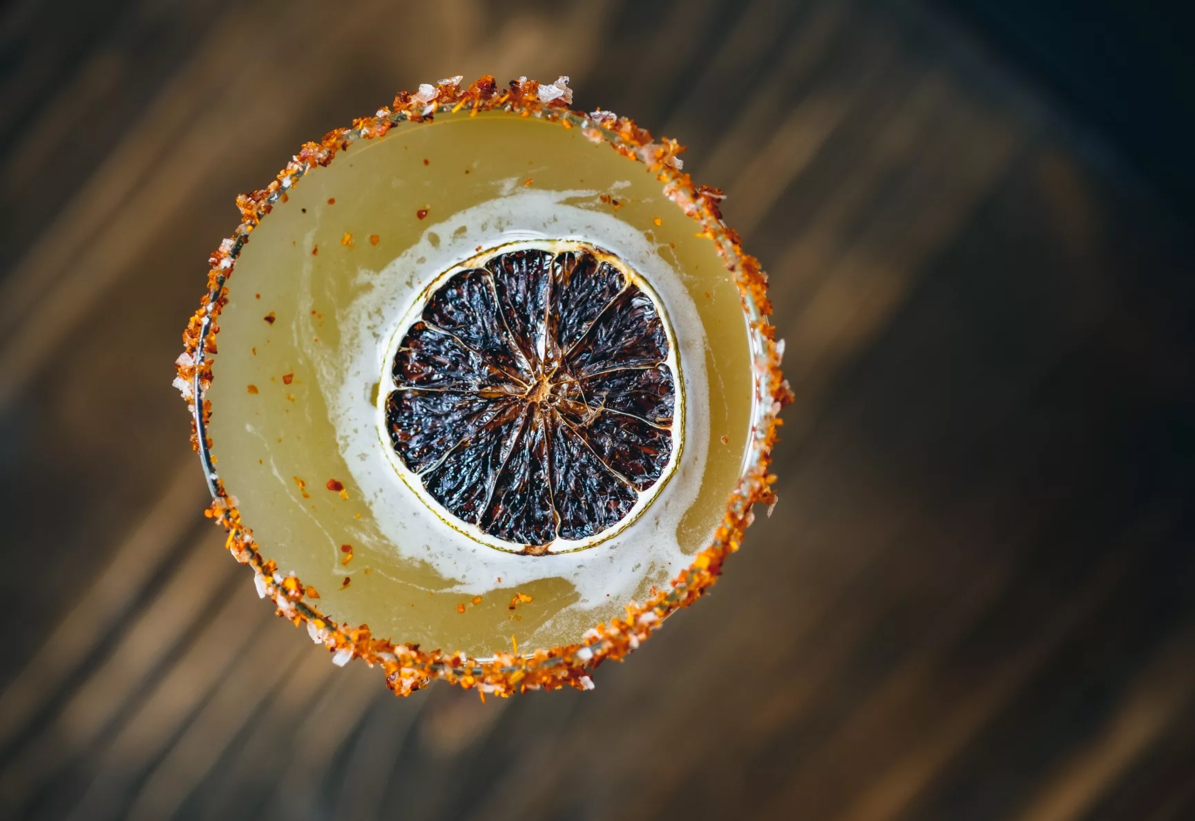 Overhead view of a cocktail garnished with a slice of dried blood orange