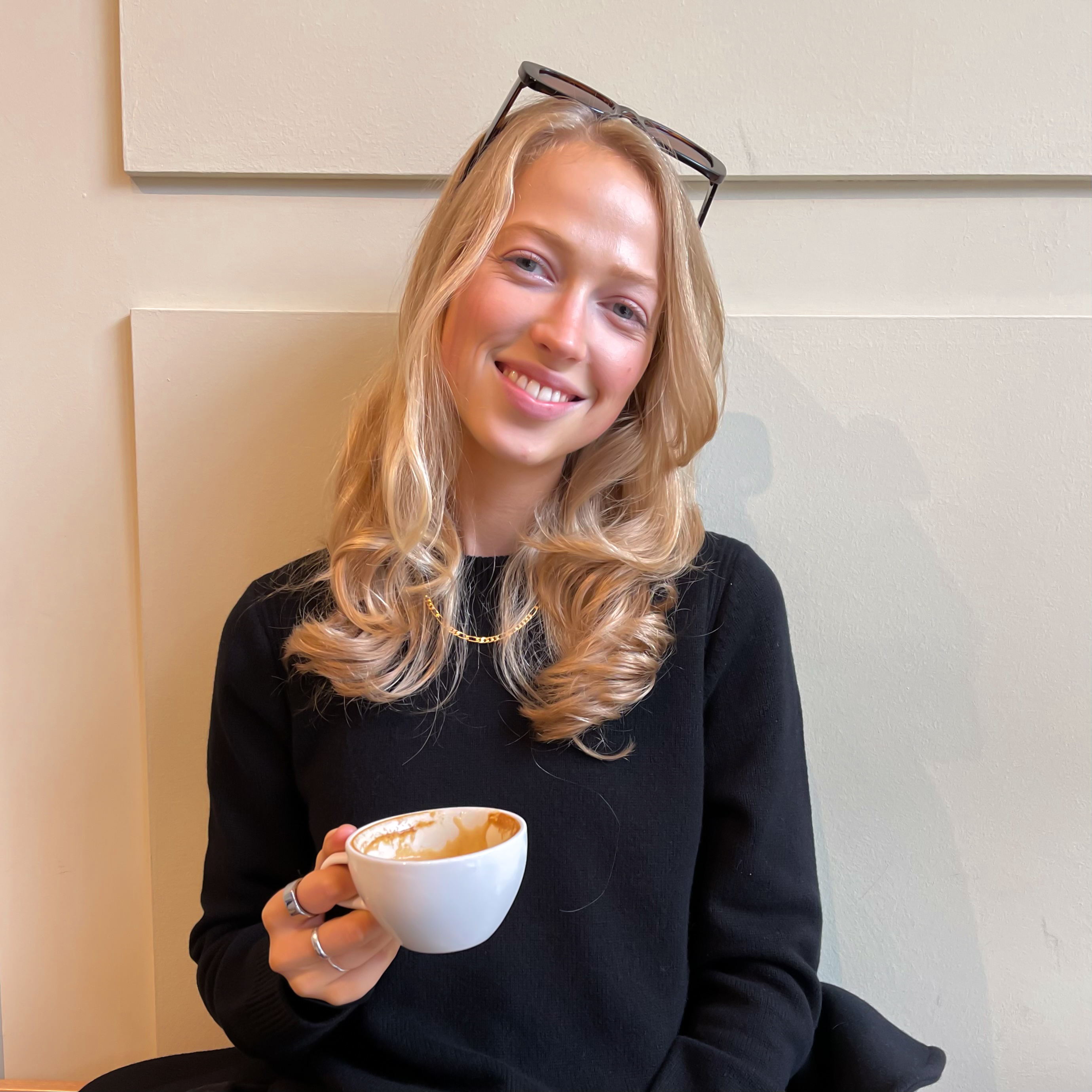 Sophie Adkin smiling at the camera, holding a cup of Coffee