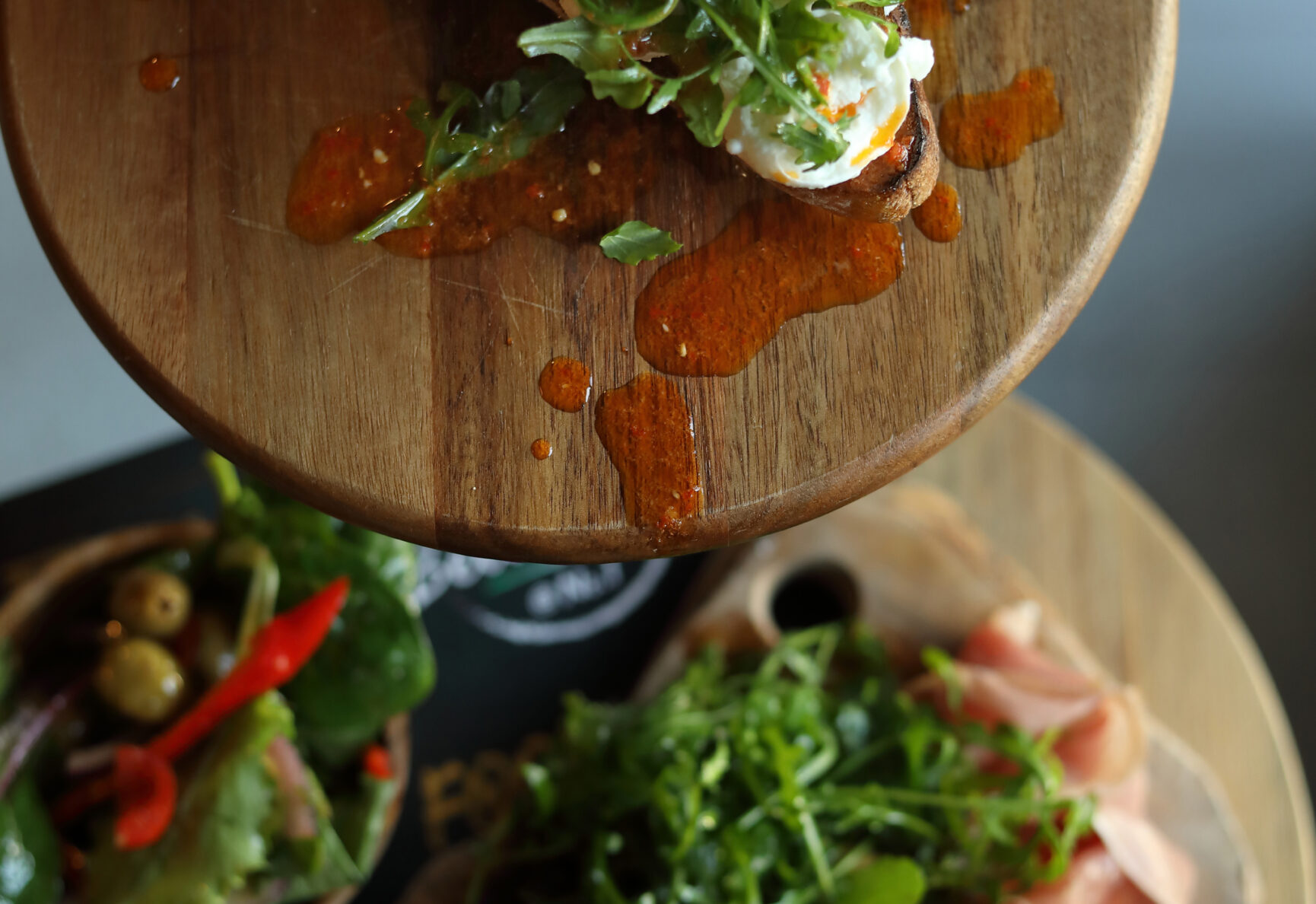 A selection of salads and charcuterie boards, available on the Bella Mia Pizza menu. Rocket, cheeses, olives and cured meats on wooden serving boards.