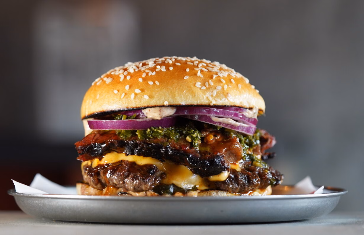 A large burger, filled with tomato, onion, lettuce and cheese.
