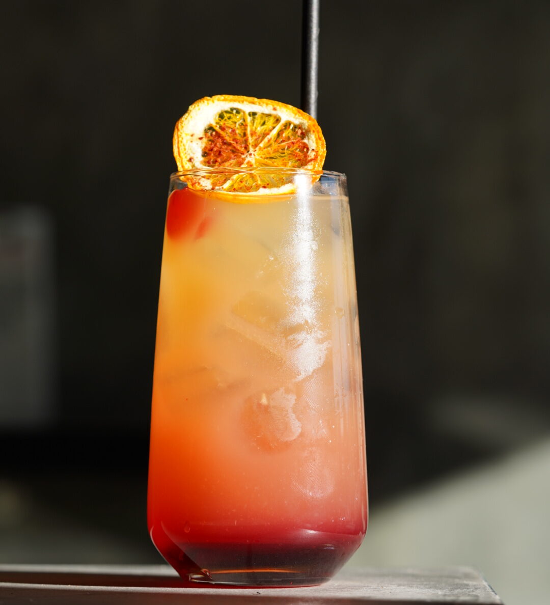 Cold, fresh cocktail with a dried slice of orange as a garnish.