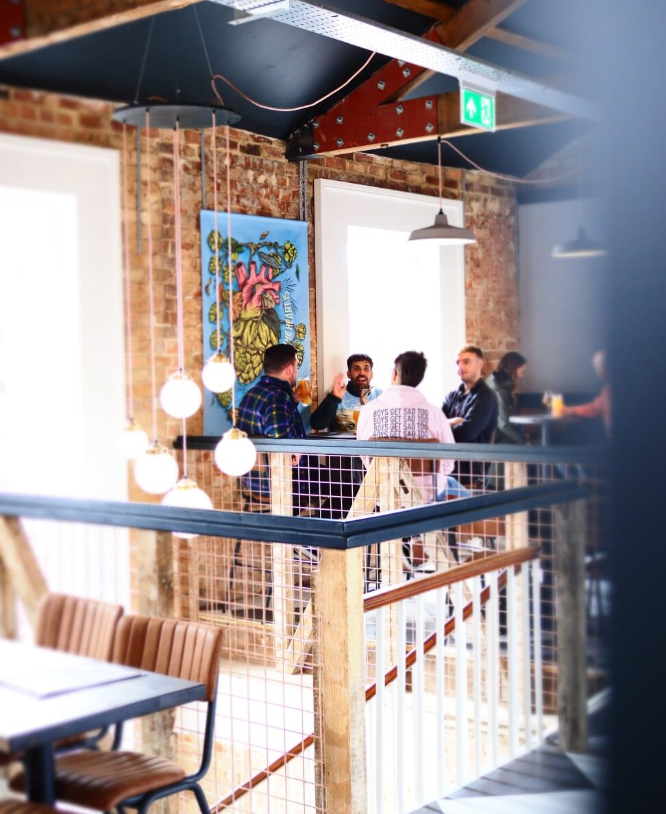 A group of friends sat upstairs in Hop Kettle in the daytime.