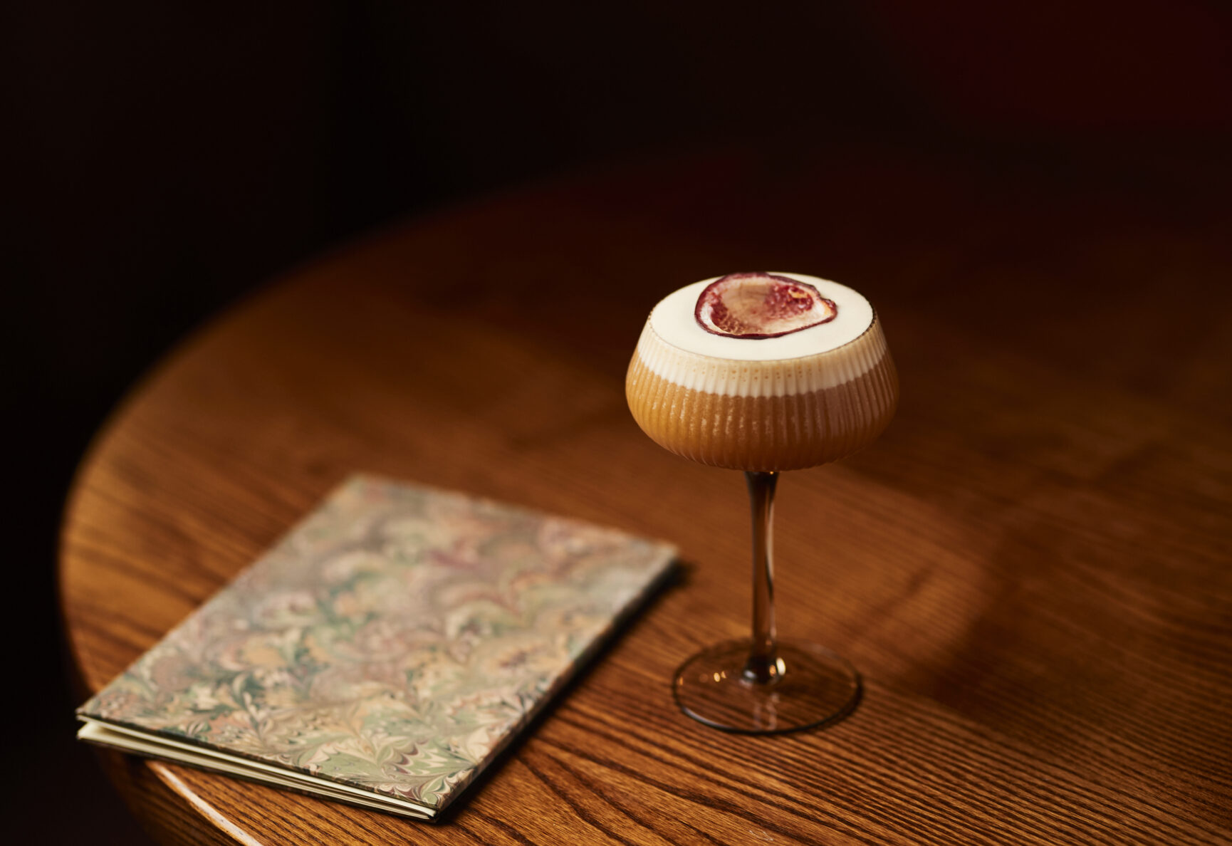 A Pornstar Martini Cocktail on a wooden table next to a menu.