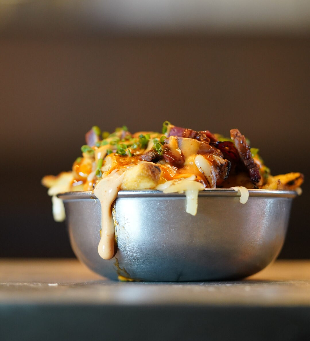 Cheese overing over the side of a serving of loaded fries in Chuck Burger Bar.