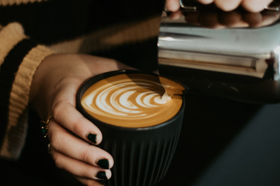 A beautiful swirl of milk as a barista pours milk into a coffee cup.