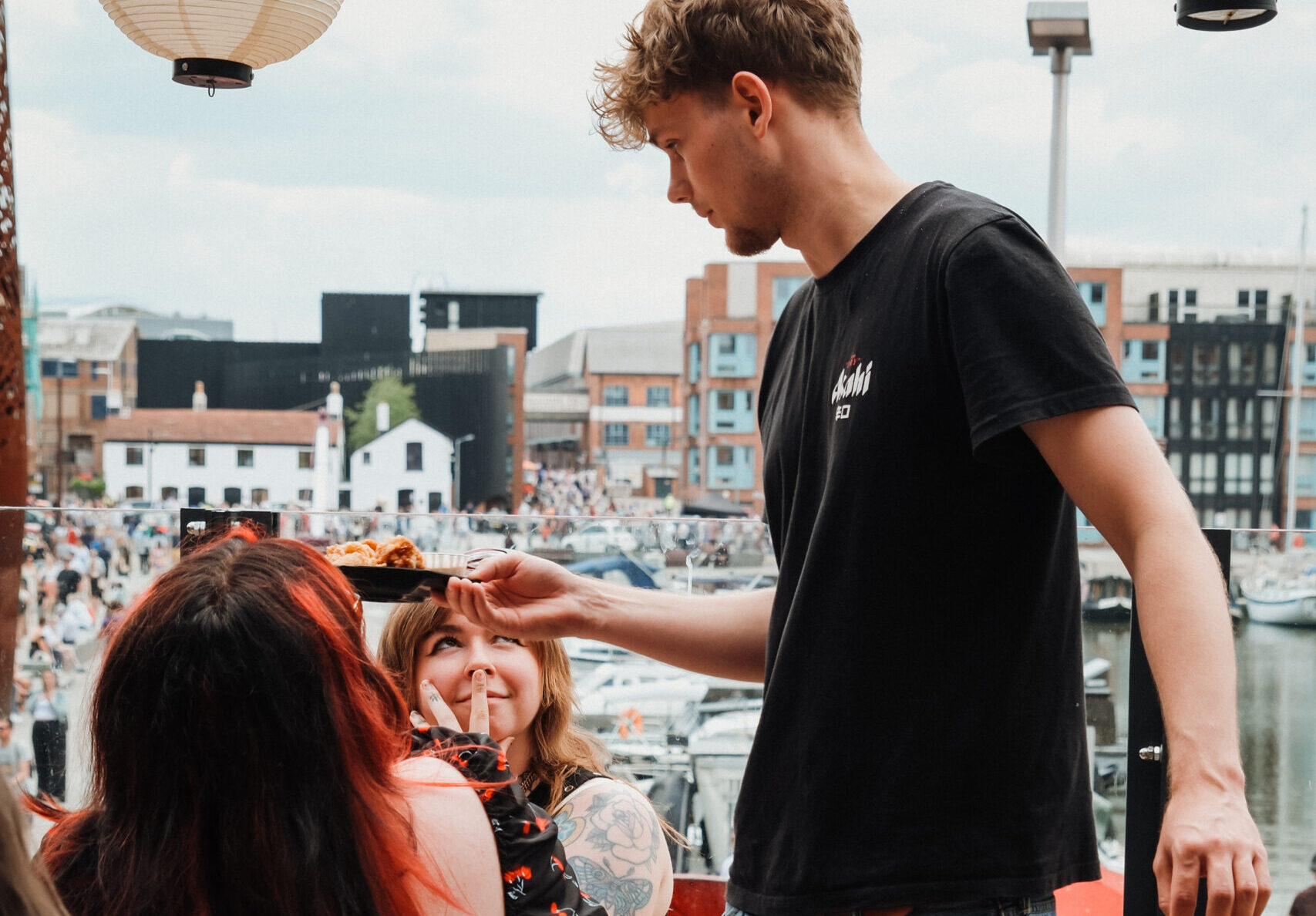 Daikoku team serving up authentic Japanese dishes with a smiling customer and a view across the Victoria Quay in the docks.