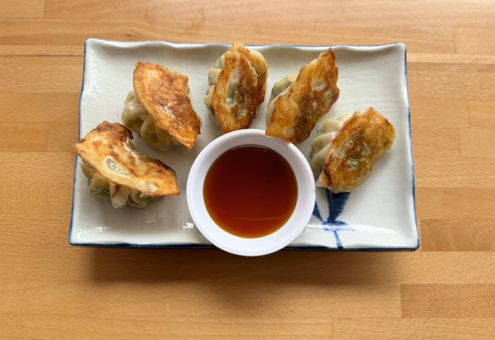 Shrimp Gyoza dumplings arranged on a plate with a Ponzu dipping sauce.