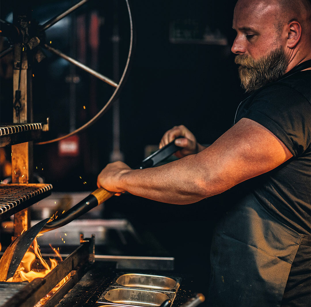Chef Lewis stoking flames in the Elote Smoker.