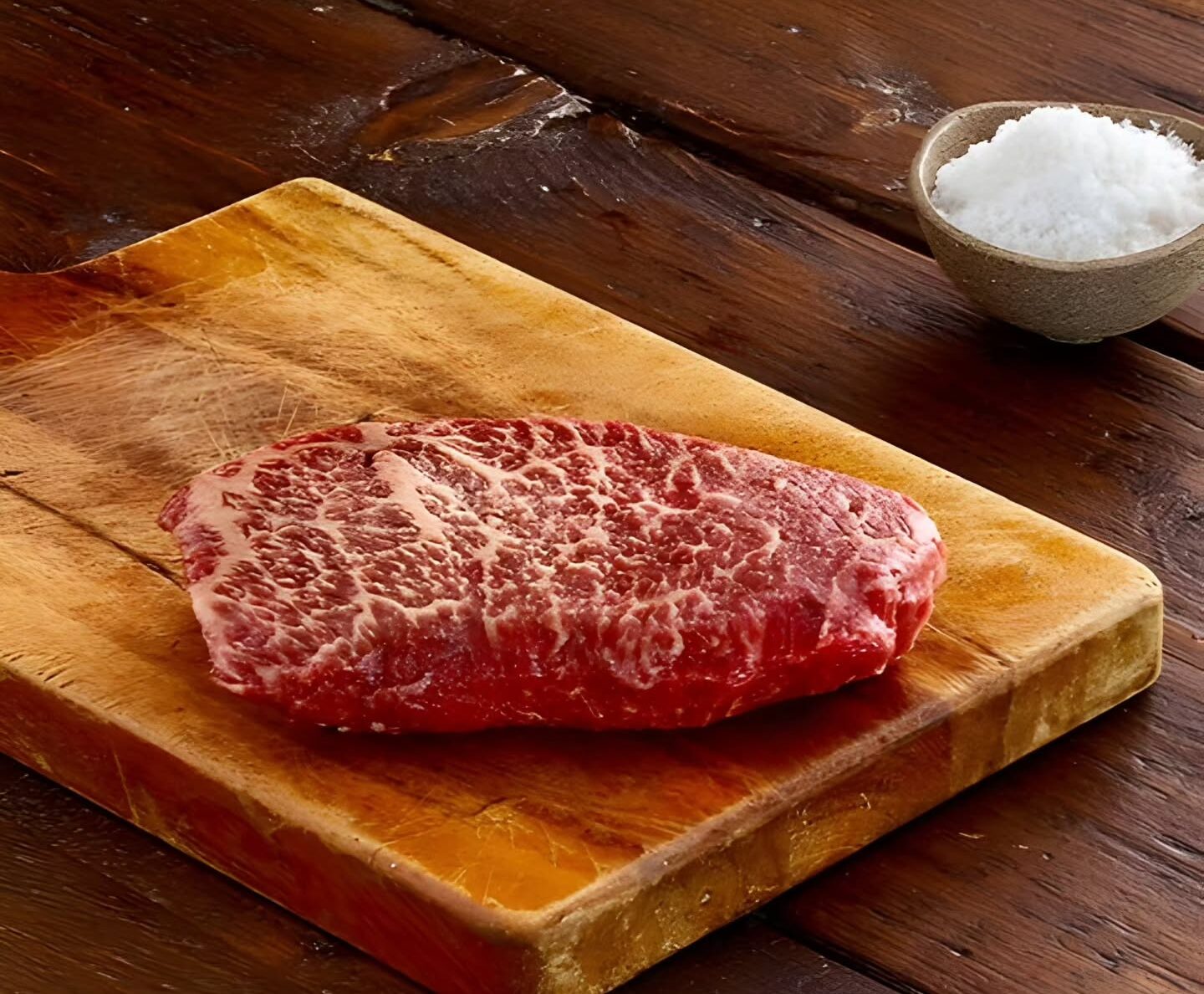 British Wagyu sits on a wooden board next to a dish of salt.